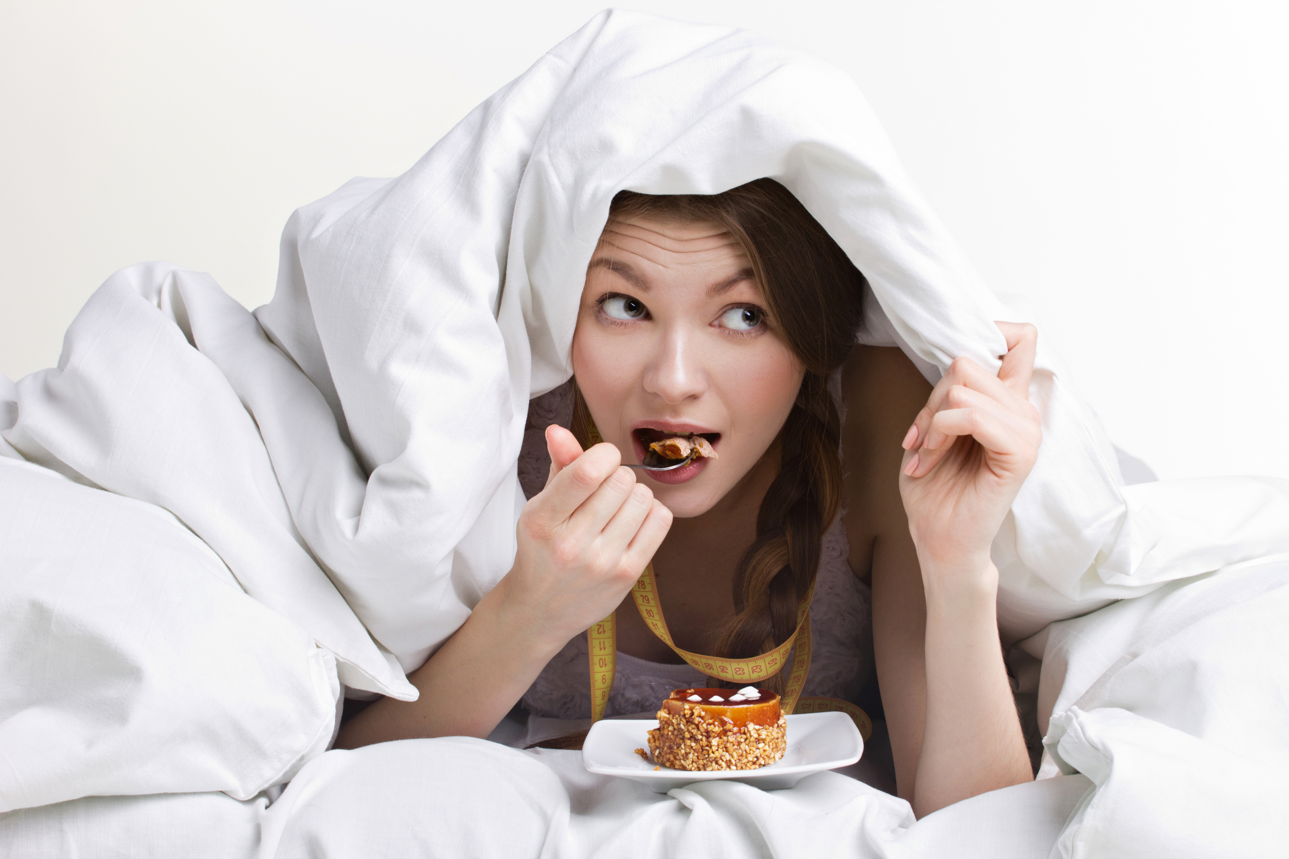 young beauty woman eating dessert under cover on white background